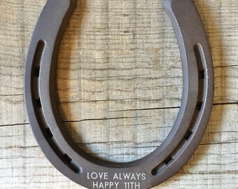 May include: A brown horseshoe with the text "LOVE ALWAYS HAPPY 11TH" engraved on the bottom.