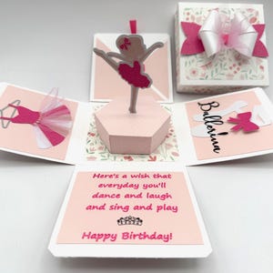 May include: A pink and white ballerina-themed birthday card. The card opens to reveal a ballerina figurine, a tutu, and the word "Ballerina". The card includes the text "Here's a wish that everyday you'll dance and laugh and sing and play Happy Birthday!"