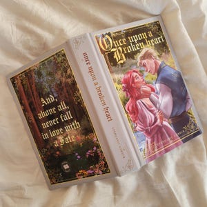 May include: A hardcover book titled "Once Upon a Broken Heart" by Stephanie Garber. The cover features a romantic illustration of a couple. The spine reads "Once Upon a Broken Heart". The back cover has the quote "And, above all, never fall in love with a Fate."