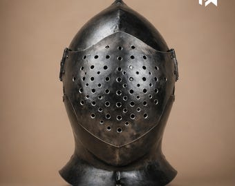 May include: A medieval-style steel helmet with a pointed top and a faceplate covered in small, evenly spaced holes. The helmet is dark gray with a slightly weathered appearance, suggesting age or use. The neck guard is curved.