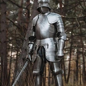 May include: A full suit of polished steel armor, including a helmet, chest plate, and articulated limbs. The knightly armor is shown in a forest setting, holding a sword. The armor is designed to protect the wearer.