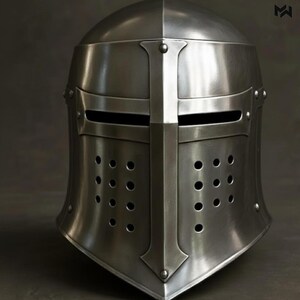 May include: A silver-colored medieval knight's helmet. The helmet features a rounded top, a horizontal visor with eye slits, and a vertical bar down the center. It has numerous small ventilation holes and is made of a reflective metal.