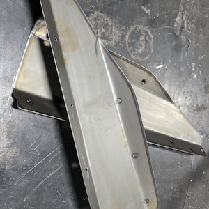 May include: Two unfinished, metallic silver metal pieces with a triangular shape and multiple holes. The pieces are likely components for a larger structure, possibly automotive or industrial.