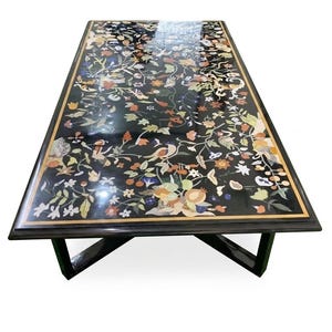 Peut inclure: Table rectangulaire en marbre noir avec un motif incrusté de fleurs, d'oiseaux et de feuillages de différentes couleurs. La table a un cadre et des pieds en bois foncé, et une bordure dorée autour du plateau.