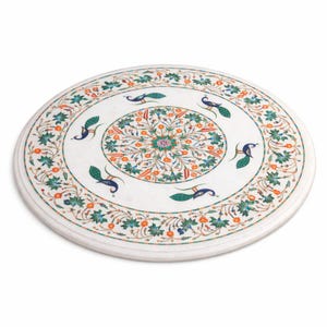 K&ouml;nnte beinhalten: Eine runde Tischplatte aus wei&szlig;em Marmor mit einem aufwendigen Intarsienmuster. Das Design zeigt ein zentrales Blumenmedaillon, Pfauen und florale Muster in Gr&uuml;n, Orange und Blau. Der Durchmesser der Tischplatte betr&auml;gt ca. 91 cm.