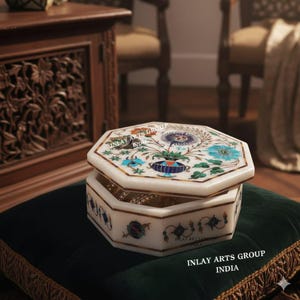May include: An octagonal white marble jewellery box with a floral inlay design in blue, green, and red. The box has a gold trim and is partially open. Text reads "INLAY ARTS GROUP INDIA".