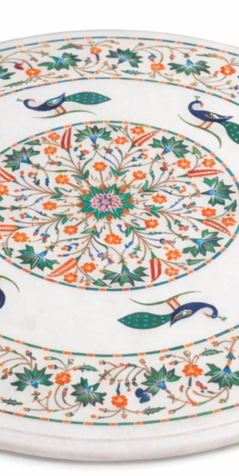 K&ouml;nnte beinhalten: Wei&szlig;er Marmortisch mit aufwendigem Blumen- und Pfaueneinlegearbeiten. Der runde Tisch hat ein zentrales Blumenmedaillon und einen Rand mit Pfauen- und Blumenmotiven in Orange, Gr&uuml;n und Blau. Durchmesser ca. 100 cm.