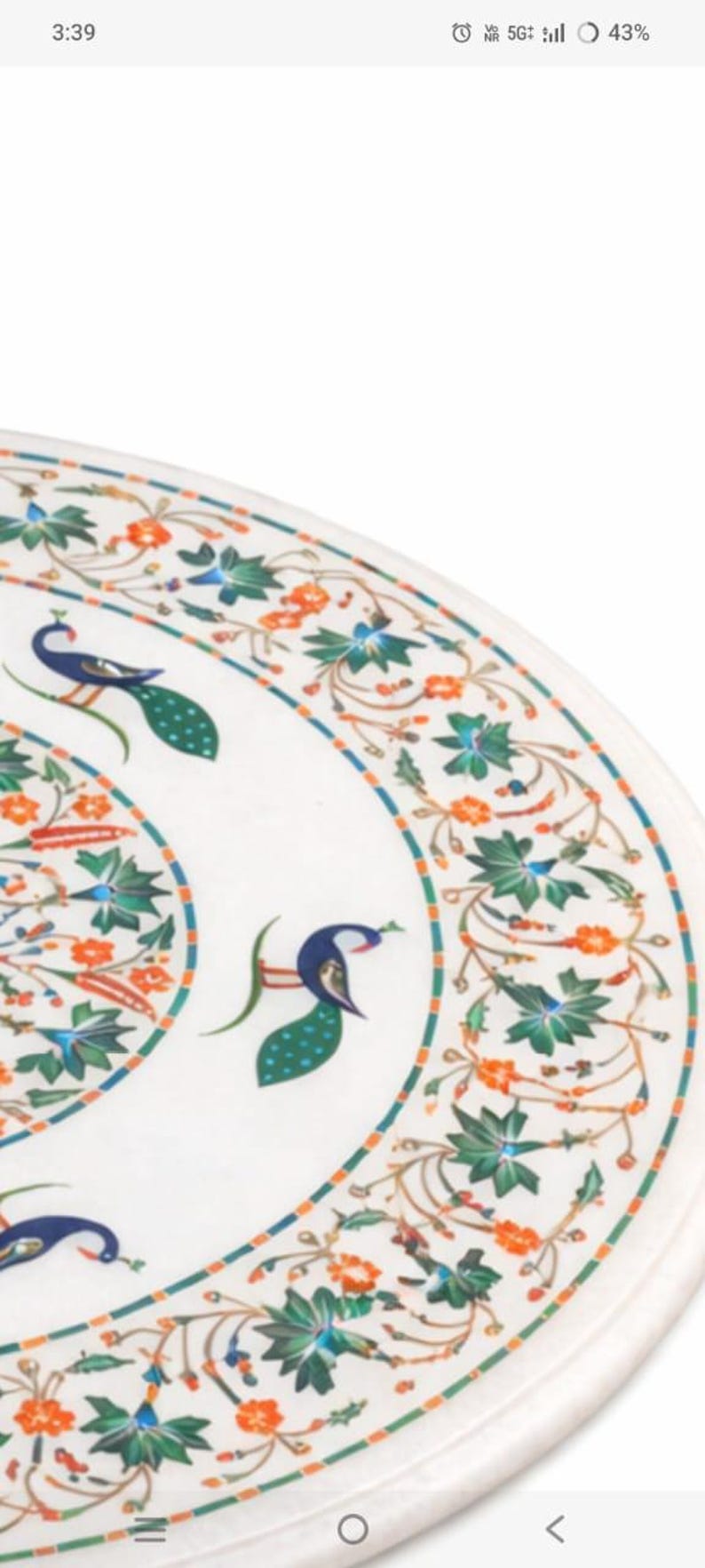 K&ouml;nnte beinhalten: Wei&szlig;er Marmor-Tischplatte mit aufwendigem Pfau- und Blumen-Intarsien-Design. Das Design weist blaue, gr&uuml;ne und orangefarbene Akzente auf. Die Tischplatte hat eine runde Form.