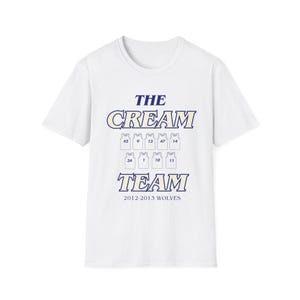 May include: White t-shirt with the text "THE CREAM TEAM" in navy blue and cream-colored lettering. Below the text are jersey numbers. The bottom of the shirt reads "2012-2013 WOLVES" in navy blue.