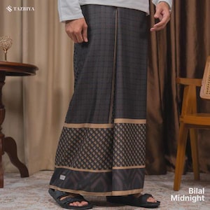 May include: A dark gray sarong featuring a repeating geometric grid pattern across the upper section, with a wide horizontal band at the hem displaying a tan and dark brown diamond weave design, finished with a solid tan border at the bottom edge.