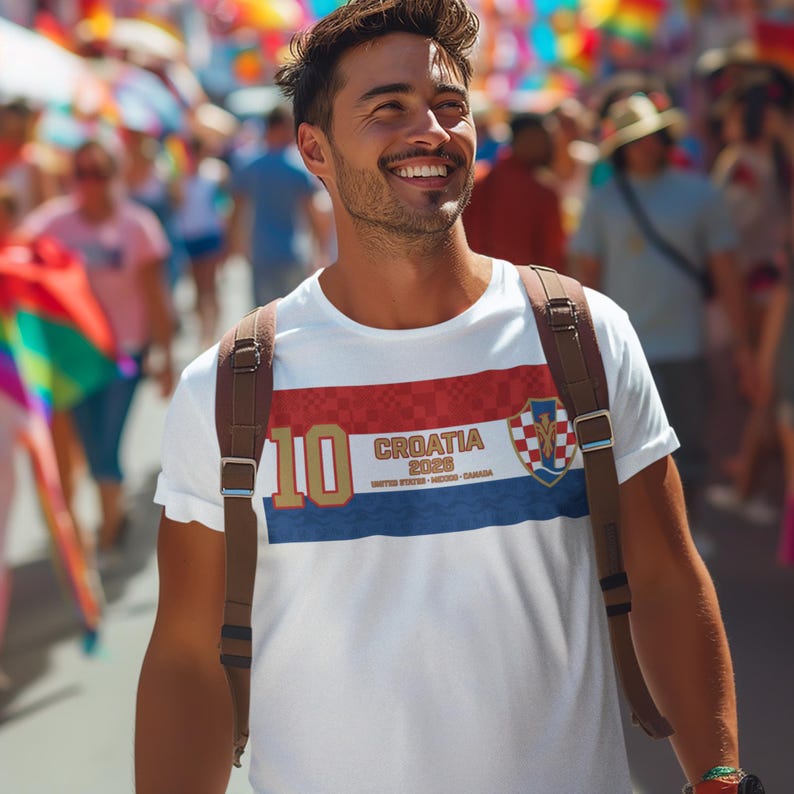 May include: A white t-shirt with a red and blue stripe design, featuring the text "CROATIA 2026" and a shield emblem. The number "10" is printed in gold. The shirt is worn by a person with a backpack.
