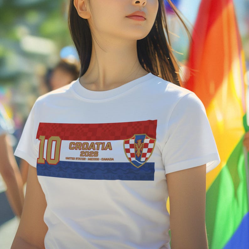 May include: White t-shirt with a Croatian flag design. The shirt features a red, white, and blue horizontal stripe design with the number "10" in gold. The text "CROATIA 2026" is printed on the shirt, along with the text "UNITED STATES - MEXICO - CANADA".
