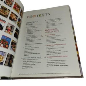 May include: Open cookbook with a table of contents. The left page displays colorful book covers with food images. The right page lists categories like "Comfort Food" and "Seasonal & Healthy" with various recipes.