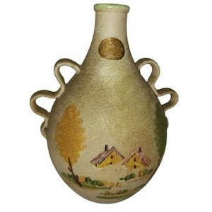 May include: A vintage ceramic vase with a landscape design. The vase has a light green and beige color scheme, with two loop handles and a small, round label. The landscape features yellow trees and houses with yellow roofs.