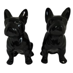 May include: Two glossy black ceramic French bulldog figurines. The dogs are in a sitting position with their ears perked up. The figurines have a smooth, reflective surface and are set against a white background.