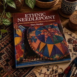 May include: A hardcover book titled Ethnic Needlepoint: Tribal Designs from Asia, Africa & the Americas by Mary Norden. The cover features a colorful, geometric needlepoint pillow design in shades of blue, orange, yellow, and red.