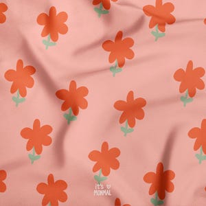 May include: A pink fabric with a repeating pattern of orange flowers with green stems. The text "it's ♡ MONMAL" is in the lower right corner. The fabric has a soft, wrinkled texture.