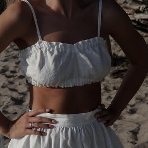 Puede incluir: Un top blanco de lino con escote fruncido y una falda blanca de lino a juego.