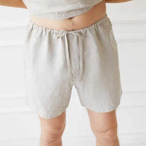 May include: Beige linen shorts with a drawstring waist. The shorts are loose fitting and have a relaxed fit.