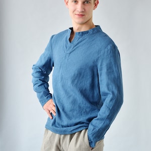 Puede incluir: Un hombre con una camisa azul de manga larga con cuello en V y pantalones de lino beige.