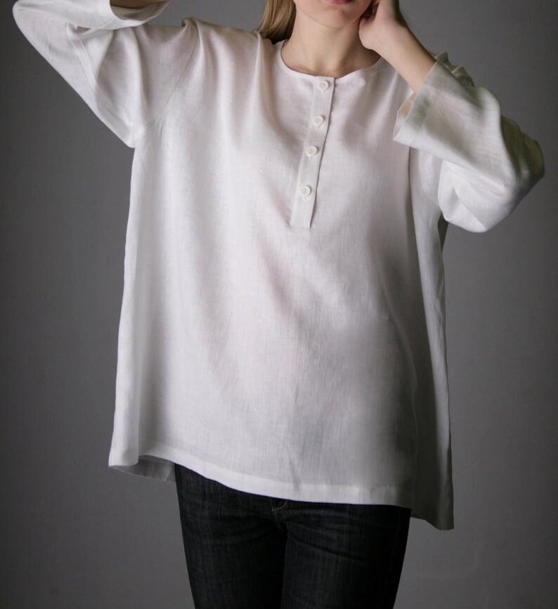 May include: A white linen shirt with a button-up placket and long sleeves. The shirt is loose-fitting and has a relaxed silhouette.