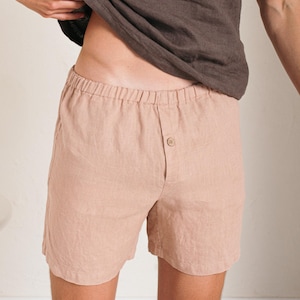May include: A pair of light brown linen shorts with an elastic waistband and a button closure. The shorts are made of a soft, breathable fabric and are perfect for warm weather.