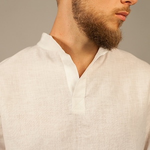 Puede incluir: Una camisa blanca de lino con cuello en V y cierre de bot&oacute;n.