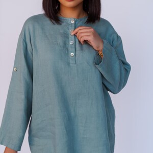 May include: A teal blue linen shirt with a button-up front and long sleeves. The shirt has a relaxed fit and is made of a lightweight fabric.