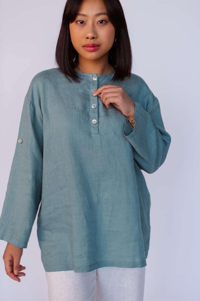 May include: A teal blue linen shirt with a button-up front and long sleeves. The shirt has a relaxed fit and is made of a lightweight fabric.