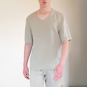 Pode incluir: Uma camisa de linho verde claro com decote em V e mangas curtas combinada com cal&ccedil;&otilde;es de linho a condizer.