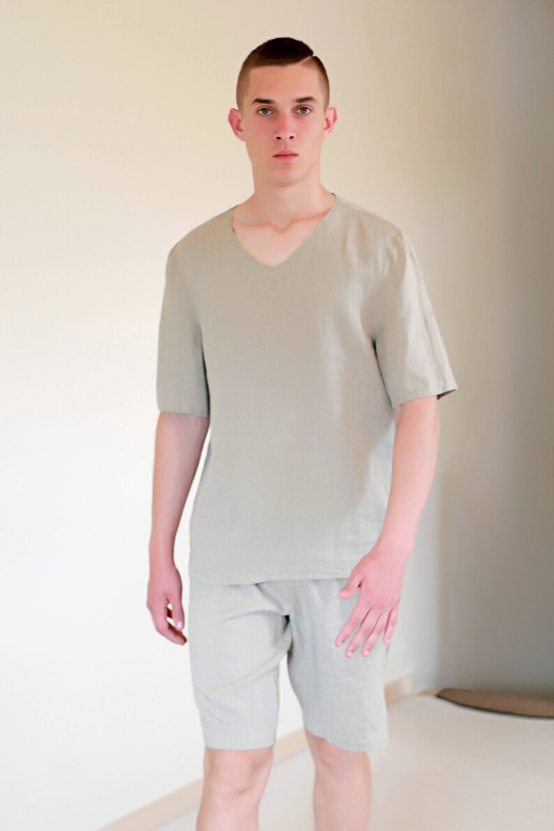 Pode incluir: Uma camisa de linho verde claro com decote em V e mangas curtas combinada com cal&ccedil;&otilde;es de linho a condizer.