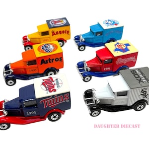 May include: A collection of diecast model trucks, each painted in the colors of different Major League Baseball teams. The trucks feature team logos and the year 1991. The teams include the Angels, Astros, Twins, Rangers, and White Sox.