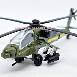 May include: A detailed diecast model of a military helicopter. The toy helicopter is primarily olive green with black rotors and accents. It features a clear cockpit and simulated weaponry, showcasing a realistic design.