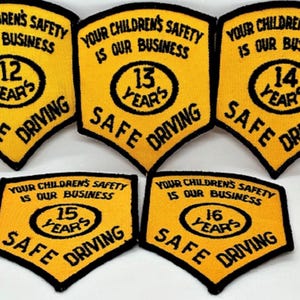 Peut inclure: Plusieurs écussons brodés jaunes et noirs. Chaque écusson porte l'inscription "YOUR CHILDREN'S SAFETY IS OUR BUSINESS" et "SAFE DRIVING". Les écussons affichent les chiffres 12, 13, 14, 15 et 16 ans.
