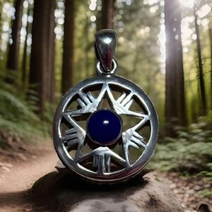 May include: A silver pendant with a five-pointed star design and a dark blue gemstone in the center. The pendant is surrounded by a circle with a repeating pattern.