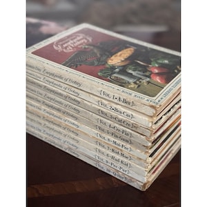 May include: A stack of vintage cookbooks titled "Woman's Day Encyclopedia of Cookery." The covers feature illustrations of food and a bird. The volumes are labeled with titles like "Vol. 1-A-Bea" and "Vol. 2-Bea-Cas."