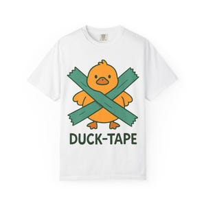 Pode incluir: T-shirt branco com um desenho de pato de desenho animado, laranja, cruzado com fita adesiva verde. O texto "DUCK-TAPE" está impresso abaixo. Uma t-shirt gráfica divertida, ideal para uso casual.