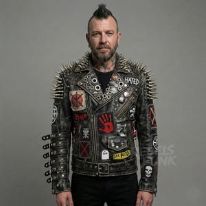 May include: Black leather jacket with silver spikes on the shoulders and collar. The jacket features various patches with text and graphics, including the word "HATED" and a skull. The jacket has a belt and multiple metal accents.