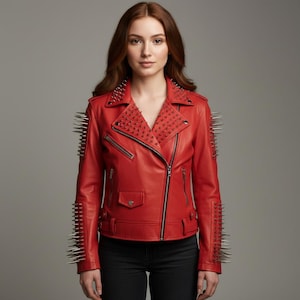 May include: A red leather jacket with silver spikes on the shoulders and sleeves. The jacket has a classic biker style with a notched collar, asymmetrical zipper, and multiple pockets. The model is wearing black pants.
