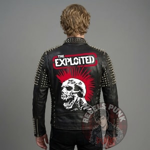 Op de afbeelding: Zwarte leren jas met zilveren metalen spikes op de schouders en kraag. De achterkant heeft een rood-witte afbeelding van een schedel met een hanenkam en de tekst "THE EXPLOITED". Een punkrock jas.
