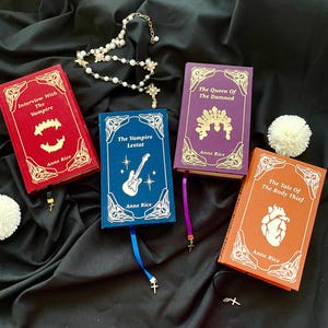 Könnte beinhalten: Vier Hardcover-Bücher mit goldfarbenen Buchstaben und dekorativen Rändern. Zu den Titeln gehören "Interview With The Vampire", "The Vampire Lestat", "The Queen Of The Damned" und "The Tale Of The Body Thief" von Anne Rice. Jedes Buch hat eine andere Farbe und ein passendes Lesezeichen.