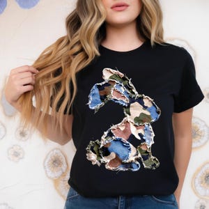Peut inclure: T-shirt noir avec un motif de lapin en patchwork. Le lapin est composé de tissus camouflage bleus, verts et marron. Le t-shirt a des manches courtes et un col rond.