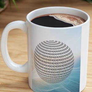 May include: White ceramic coffee mug filled with dark coffee. The mug features a graphic of a binary code sphere on a gradient blue and white background. The mug has a curved handle and is sitting on a wooden surface.