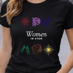 May include: Black t-shirt with the text "Women in STEM" and colorful science-themed graphics. The graphics include an atom, DNA, a plant, test tubes, a sphere, and a circuit board.