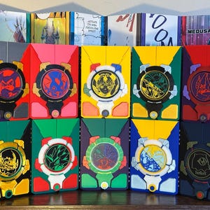 May include: A collection of colorful, rectangular boxes with circular, detailed designs on the front. Each box features a unique color scheme, including red, yellow, green, and purple, with intricate artwork and accents.