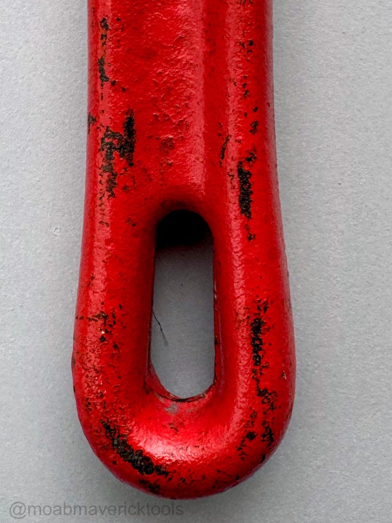 May include: Close-up of a red metal tool with a loop. The tool has a textured surface with areas of black wear and tear. The @moabmavericktools watermark is visible at the bottom.