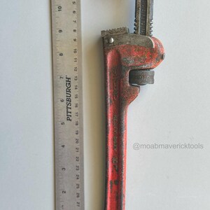May include: A vintage red and black heavy-duty pipe wrench with a Pittsburgh ruler. The wrench is approximately 10 inches long. The wrench has a textured handle and adjustable jaws. The text "Heavy Duty 10" is visible on the handle. The Instagram handle @moabmavericktools is also visible.