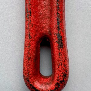 May include: Close-up of a red metal tool with a textured surface and a loop at the end. The red paint is chipped, revealing black underneath. The text "@moabmavericktools" is at the bottom.