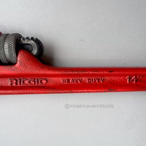 May include: A red Ridgid heavy-duty pipe wrench. The wrench is 14 inches long and features a textured grip and adjustable jaws. The tool is designed for heavy-duty use and is a vibrant red color.