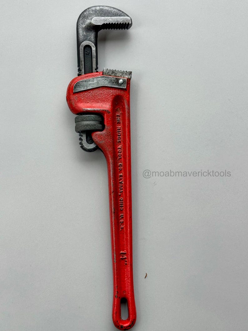 May include: A red 14-inch pipe wrench with a black adjustable jaw. The wrench has the text "THE RIDGE TOOL CO. ELYRIA, OHIO, U.S.A." and the Instagram handle "@moabmavericktools" on the handle.